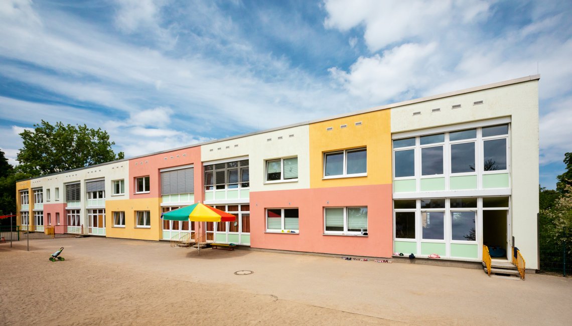 Das farbenfrohe Geb&auml;ude der Tagesgruppe Wendorf mit einem bunten Sonnenschirm davor
