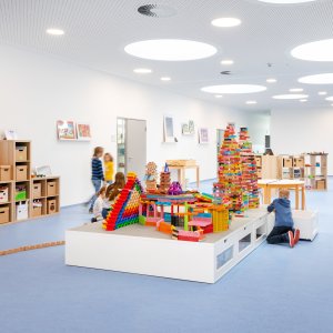Kinder spielen in einem Flur und bauen mit Bausteinen.